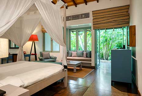 Spacious luxury hotel room at Wallawwa, featuring a four-poster bed, cozy seating, and a private outdoor space.